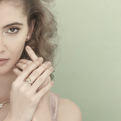 Mulher com brincos guardian femininos e aneis finos da Carmo Joalheiros em fundo verde