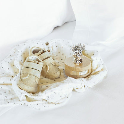 caixa de música anjo topázio em madeira com anjo prateado e sapatinhos de bebé sobre manta